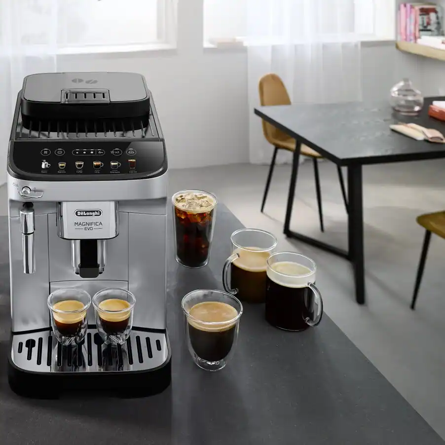 De’Longhi Magnifica Evo on a kitchen counter beside four espresso and milk drinks
