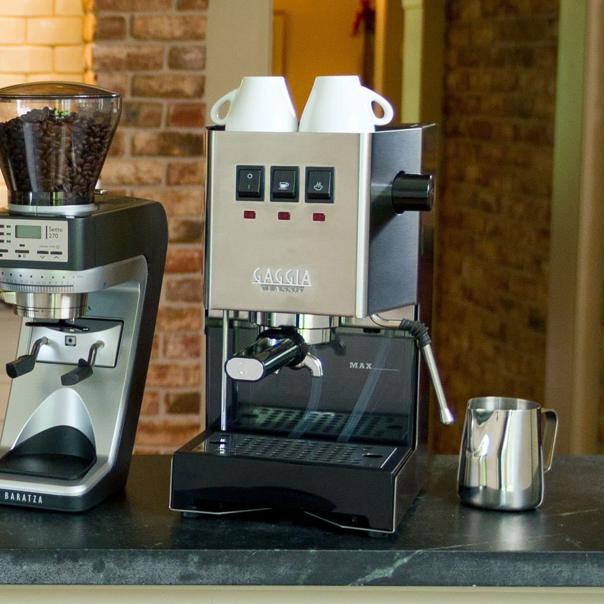Gaggia Classic Pro E24 in stainless steel on a counter, with a separate grinder and a milk jug beside it; the machine has no grinder of its own