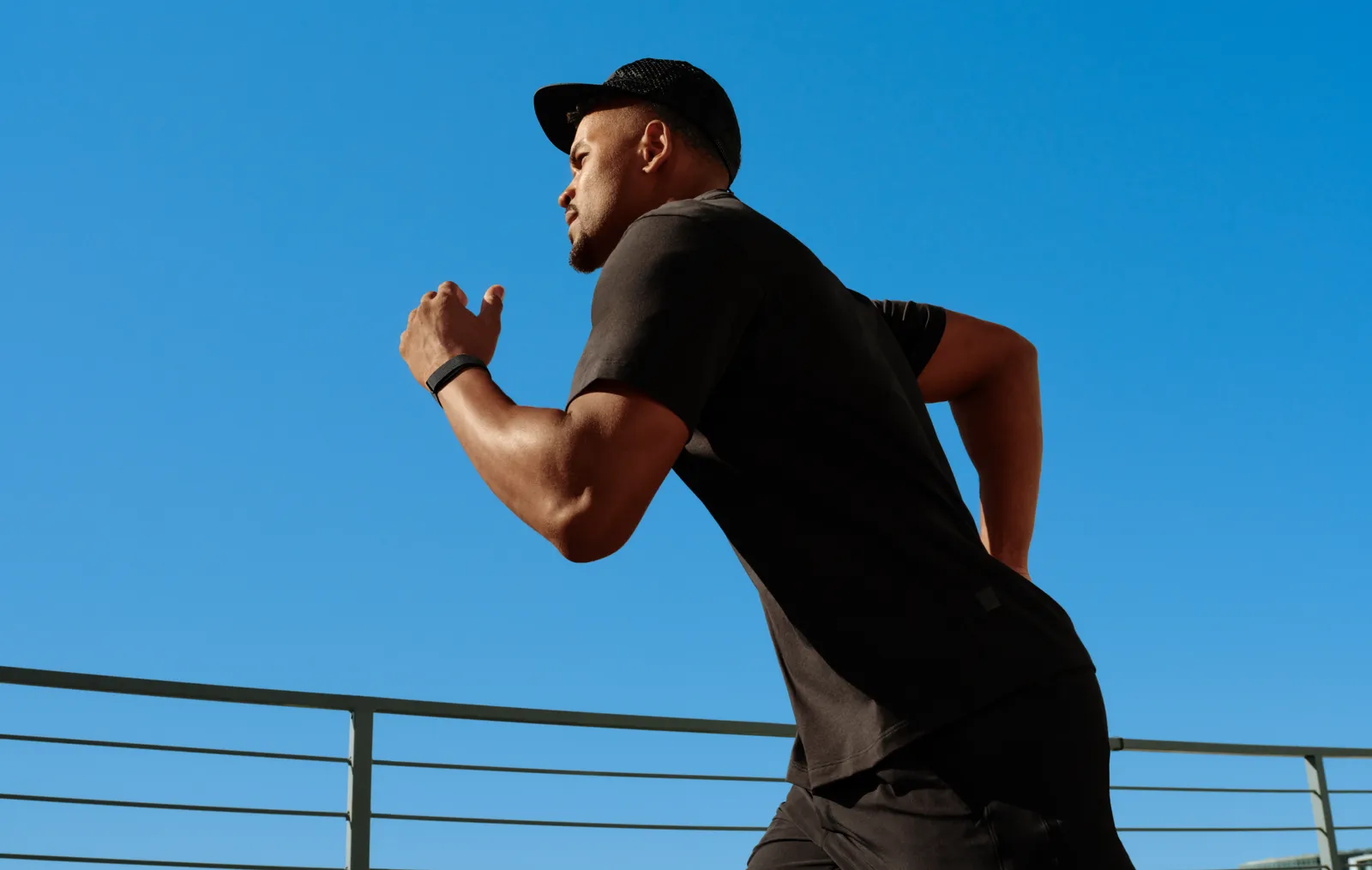 A man running outdoors wearing Google Fitbit Air with a Performance Loop band in Obsidian